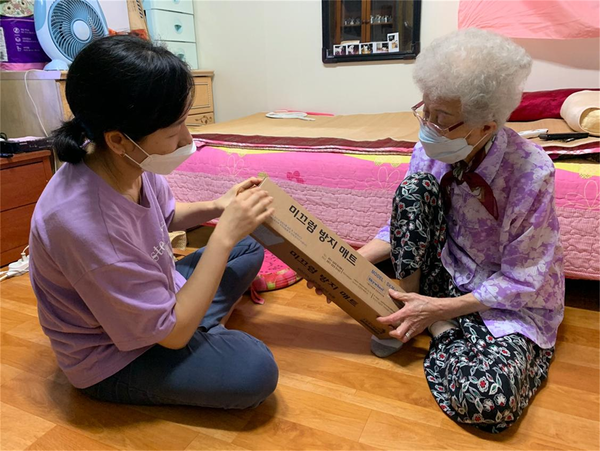 어르신에게 미끄럼 방지매트를 전달하고 설명하는 모습 / 사진 = 광진구 제공.