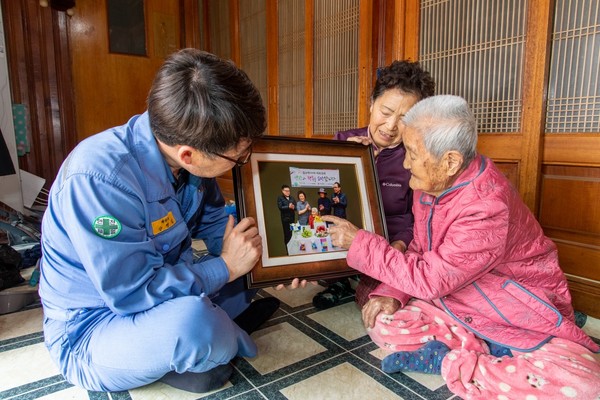 광양제철소 산하 '찰칵' 재능봉사단이 김소악 할머니(맨 오른쪽)에게 장수기념 사진을 전달했다./광양제철소 제공