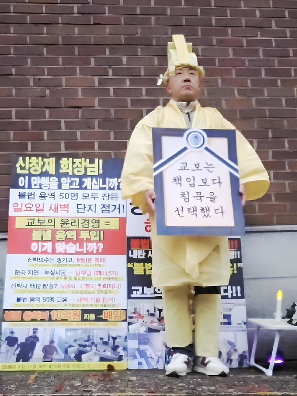 25일 오전 서울 성북동 교보생명 회장 자택 앞에서 상복 차림의 시행사 관계자가 "교보는 책임보다 침묵을 선택했다"는 문구가 적힌 영정틀을 들고 시위를 벌이고 있다. / 사진=제보자